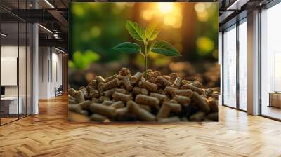 A small green plant sprout growing from a pile of wood pellets with the sun shining in the background. Wall mural