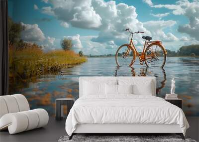 A vintage bicycle sits in the shallow waters of a lake with a blue sky and fluffy clouds overhead. Wall mural