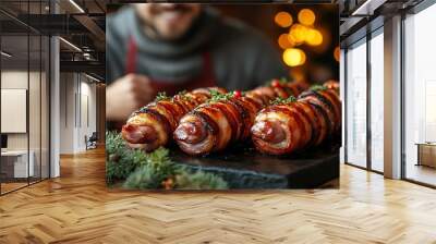 Delicious bacon wrapped appetizers on a wooden cutting board with a man in the background. Wall mural