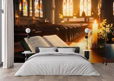 Open Bible on a pew in a church with a lit candle and a bouquet of flowers in the foreground. Wall mural