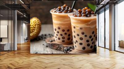 Two glasses of brown bubble tea with tapioca pearls on a wooden table with durian fruit. Wall mural