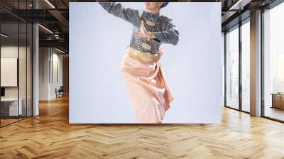 A beautiful Malaysian traditional female dancer performing a cultural dance routine in a traditional outfit on a stage. Full length portrait. Wall mural