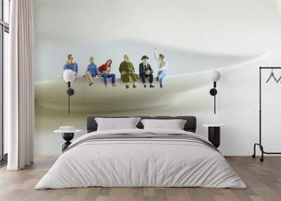 A group of miniature figures of people sitting on a plate and discussing problems. Wall mural