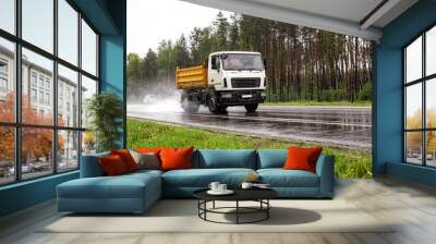 A modern dump truck for transporting bulk cargo drives on the highway in rainy weather. Safe driving in bad weather conditions. Copy space for text, outdoors Wall mural