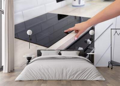 Modern induction hob in the kitchen. A woman's hand sets the heating power of the burner, ceramic Wall mural