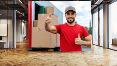 Smiling delivery man giving thumbs-up next to truck filled with boxes for logistics service Wall mural