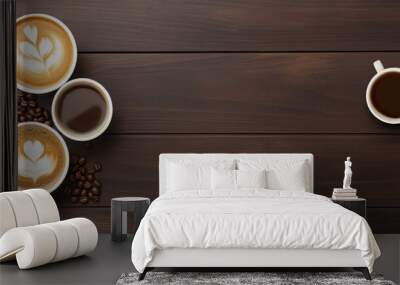 Top-down view of an assortment of coffee drinks including lattes with heart designs and black coffee, with scattered coffee beans on a wood background. Copy space concept Wall mural