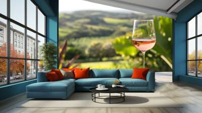 Tranquil outdoor setting with a glass of chilled refreshing ros wine placed on a table surrounded by a beautiful natural landscape  This image offers ample space for adding text or overlays Wall mural