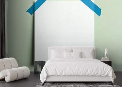 Mockup poster A blank white paper sheet taped to a wall with two blue pieces of tape. Wall mural