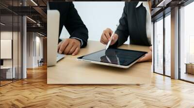 Two professionals analyzing data on a tablet at a desk. Wall mural