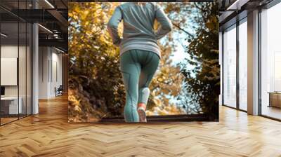 Active woman running upstairs in park, daily workout routine, fitness concept. Wall mural