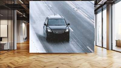 Car driving on a highway with wet slippery asphalt during a snow storm.  Wall mural