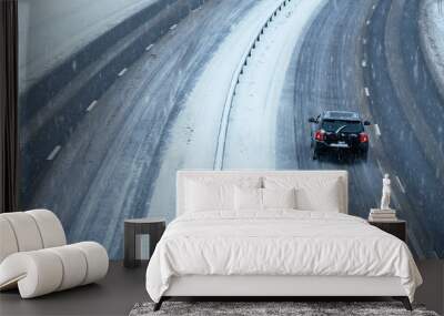 Cars driving on a highway in a blizzard with the road covered in snow and ice on a cold winters day. Wall mural