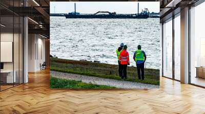 Inspectors in reflective vests and hardhats overseeing the construction of a new sea port for the Fehmarn belt tunnel project that will link Denmark and Germany. Wall mural