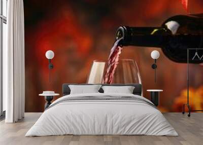 A bottle of red wine is poured into a wine glass Wall mural