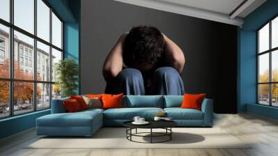 boy praying in poverty with tears in his eyes with no help crying alone and all by himself with black background stock photo Wall mural