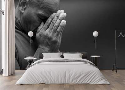 man praying to god with hands together Caribbean man praying with black background with people stock photo Wall mural