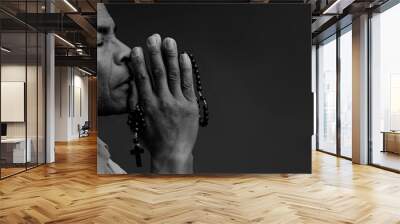 man praying to God with hands together with black background stock photo Wall mural