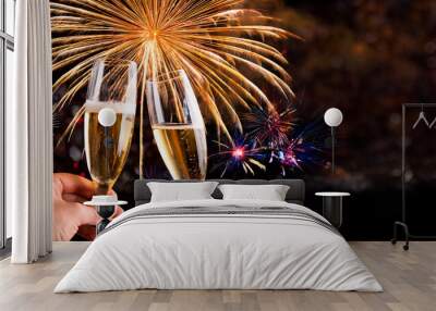 Brinde com taça de champagne e decoração dourada para celebração de ano novo e fogos de artificio ao fundo. Wall mural