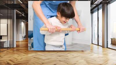 Physiotherapist and kid walking in rehabilitation center. Doctor supports a children with cerebral palsy during physiotherapy treatment. High quality photo. Wall mural