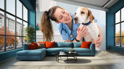 Young happy veterinary nurse smiling while playing with a dog. High quality photo Wall mural