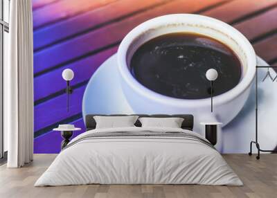 A cup of hot espresso coffee on plate on wooden table in morning rush time with colorful lighting Wall mural