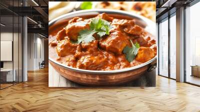 A close-up of a bowl of chicken tikka masala with fresh cilantro, served with two pieces of naan bread on the side. Wall mural