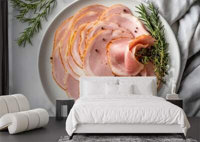 A white plate with thinly sliced, spiral-shaped ham garnished with rosemary and peppercorns. Wall mural