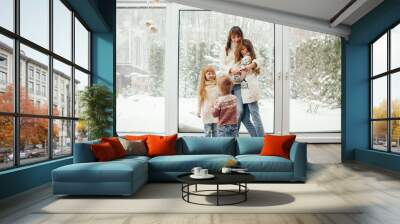 Beautiful mother with children. Family at home. People standing near winter windows Wall mural