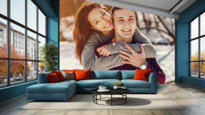 Cute couple have fun. Boy and girl in a winter park. Man in a red sweater. Brunette in a gray sweater Wall mural