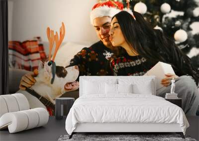 Cute couple sitting at home near christmas tree Wall mural