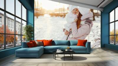 Family have fun in a winter park. Stylish mother in a pink jacket. Little girl in a winter clothes. Wall mural