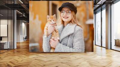 Fashion girl in a winter city. Lady with little cat Wall mural