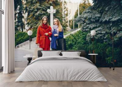 two beautiful and stylish girlfriends walking around the spring city with packages and shopping Wall mural