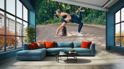 Two girls training in a summer forest. Friends have fun in a park. Sports ladies in a black sportsuit Wall mural