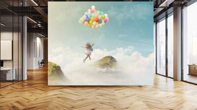 Little girl holding colorful balloons, jumping from one mountain top to the other; success/achievement concept, fantasy background with copy space Wall mural