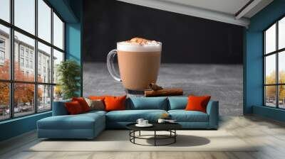 Side view of delicious cappuccino coffee with milk foam sprinkled with cinnamon in a transparent glass mug on a gray background, horizontal format Wall mural