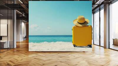 Planning summer travel with a yellow suitcase and a stylish large hat on a sandy beach. Enjoy a holiday with a backdrop of blue skies and the ocean. Perfect for a summer travel banner, with ample spac Wall mural