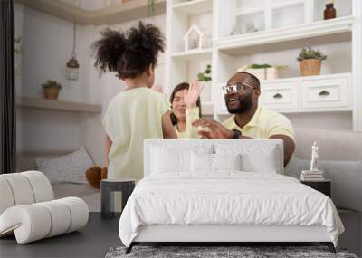 Happy African American family doing activities with daughter at home. Wall mural