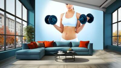 Dumbbells, fitness and portrait of woman weightlifting in studio on blue background for training. Bodybuilding, exercise and workout with serious athlete at gym for physical power or strength Wall mural