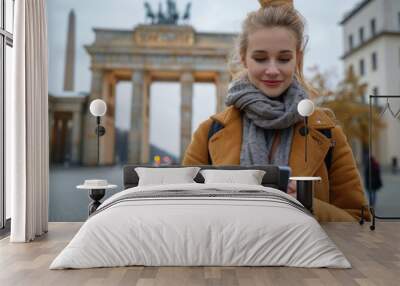 Blonde beauty at Brandenburg Gate: Young woman using phone in Berlin, Germany Wall mural