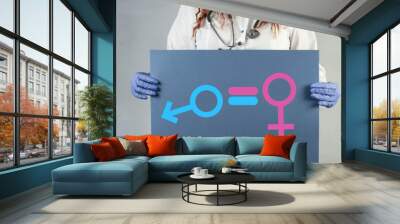 The doctor holds a poster with a female and male symbol. The concept of gender equality. Wall mural