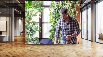 Closeup of business man enjoy working on computer in his pleasant studio home office with green houseplant. Wall mural