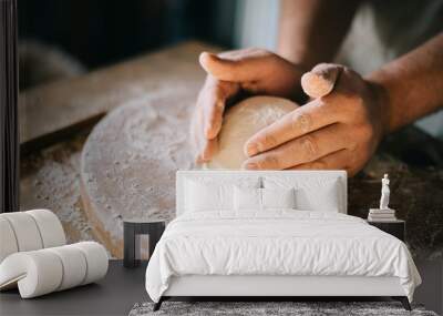 Man kneading and baking homemade pizza dough in the kitchen. Closeup on baker's hands preparing loaf of bread. Wall mural