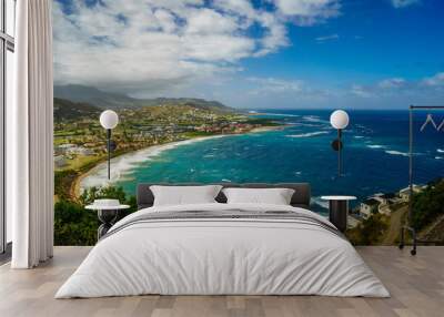 A view over St. Kitts Island with residential area and beaces on the foreground and lush green hills on the background Wall mural