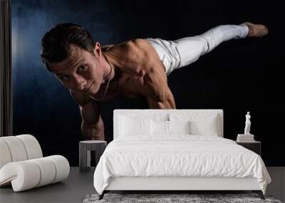 Muscular man making planche on black black background Wall mural