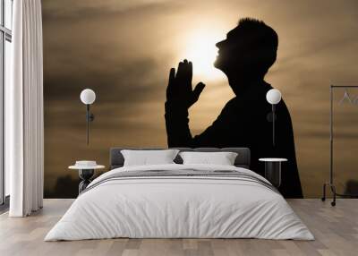 Silhouette of Man pray on during sunset. Repentance, regret and hope concept  Wall mural