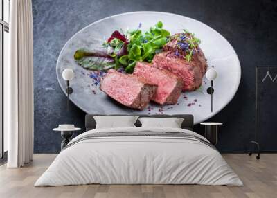 Barbecue dry aged wagyu roast beef natural sliced and offered with lettuce and herbs as closeup on a modern design plate with copy space Wall mural