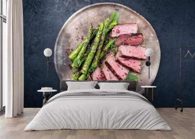 Barbecue dry aged wagyu roast beef steak with green asparagus and lettuce offered as top view on a rustic modern design plate Wall mural