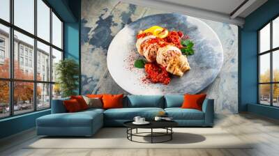 Fried calamari tubes stuffed with rice in salsiccia mince tomato sauce served as close-up on a design plate with copy space Wall mural